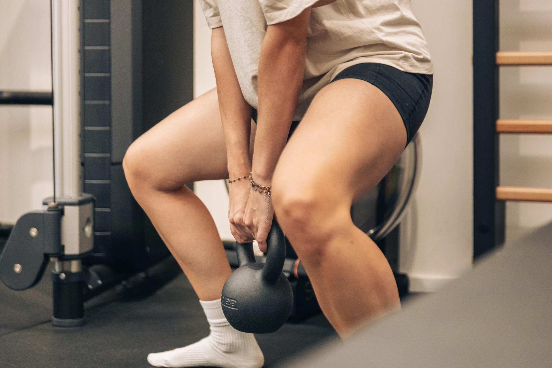 Female patient lifting a kettlebell with bent legs