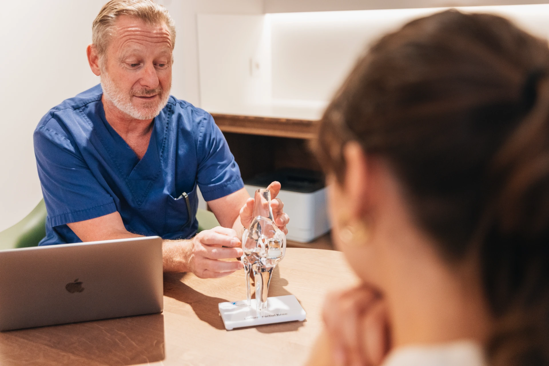Consultation entre un chirurgien orthopédiste et une patiente, modèle de genou sur la table